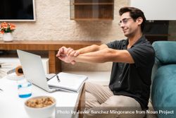 Man stretching while working from home with laptop and notepad 5lVRZ7