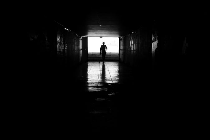 Silhouette of person walking confidently through underground tunnel