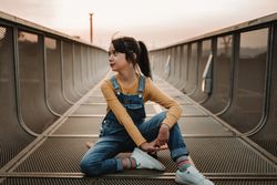Girl sitting on skateboard on walkway