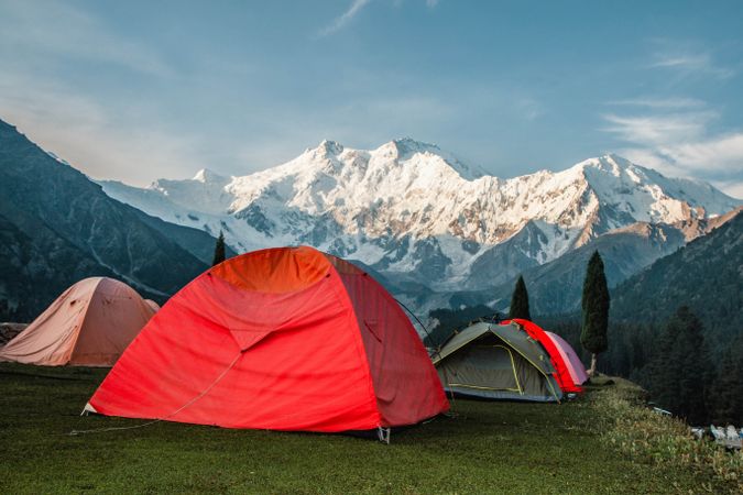Red tents camping looking at snow capped mountains in Pakistan