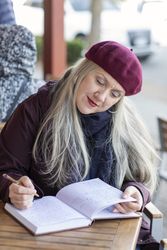Older woman writing in a notebook at a cafe