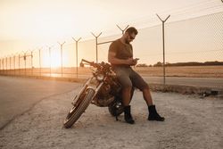 Man sitting on motorcycle and surfing mobile