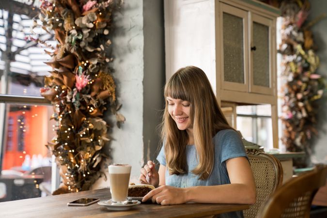 Cheerful woman using a phone in cafe