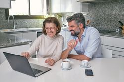 Mother and mature son using laptop together