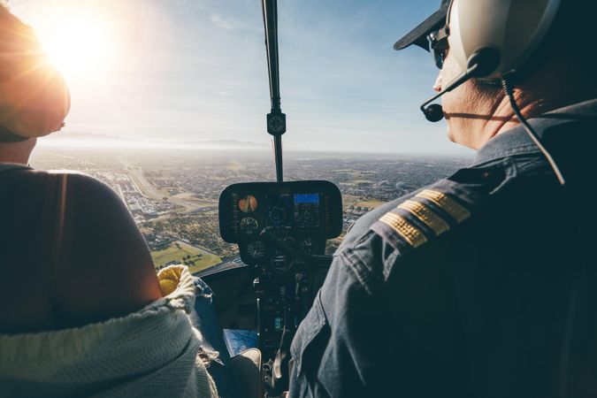 Rear view of two pilots flying a helicopter on sunny day