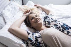 Portrait of a happy, relaxed adult woman lying on a bed