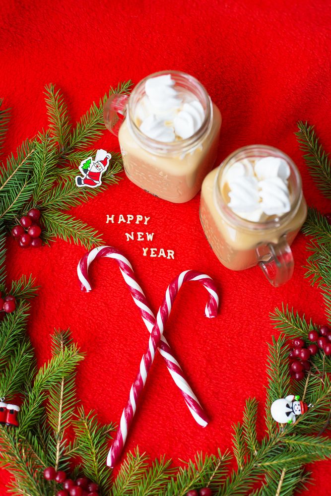 Closeup of marshmellou cocoa and candy on a red background. The inscription Happy New Year