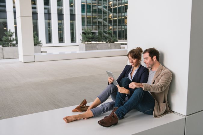 Businesspeople hugging and using tablet on street