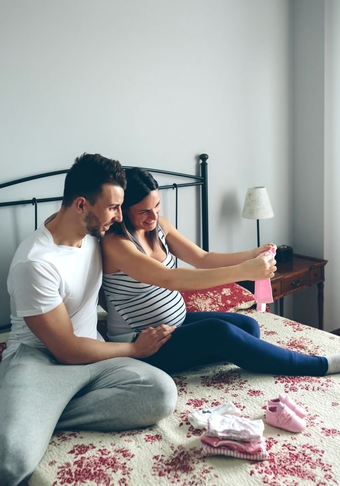 Man and pregnant woman looking baby clothes