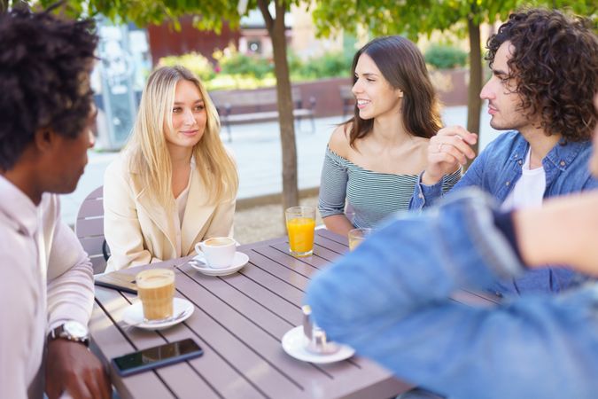 Friends having a conversation over coffee and juice at outside table