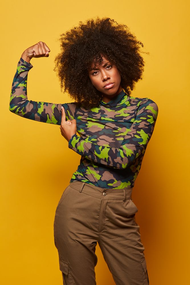 Powerful woman in military clothes flexing biceps