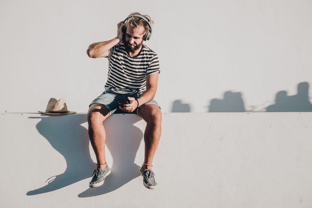 Young male sitting with smartphone and headphones