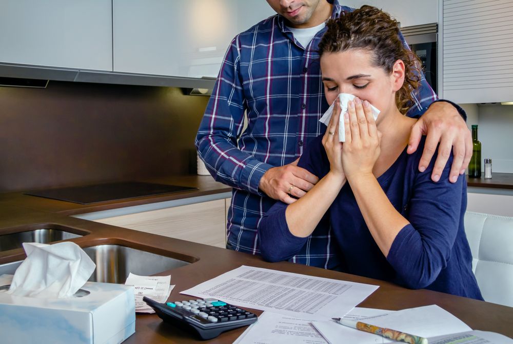 Woman crying as she review bills with her partner in ktichen