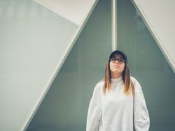 Young woman with glasses standing against wall