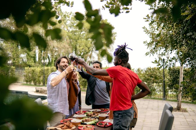 A diverse group of friends cheerfully toasting with drinks at an outdoor party