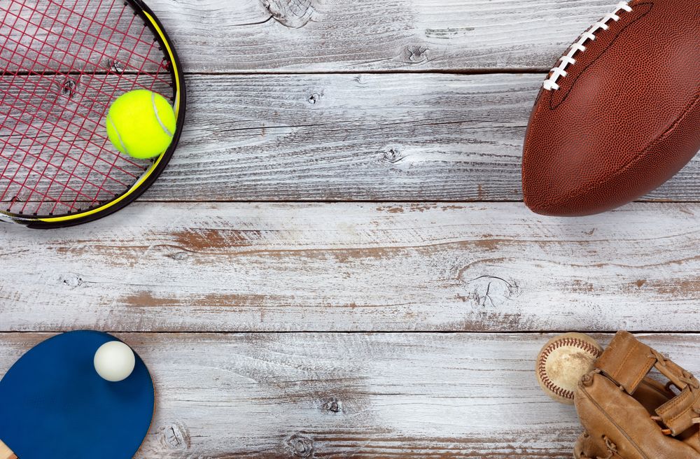 Sports equipment placed on corners of rustic wooden background
