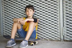 Casual dressed young serious teen skater outdoors