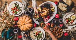 Autumnal table with squash and candles with two hands toasting with glasses of wine, vertical