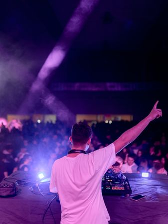 DJ raising hand while playing on stage in a club