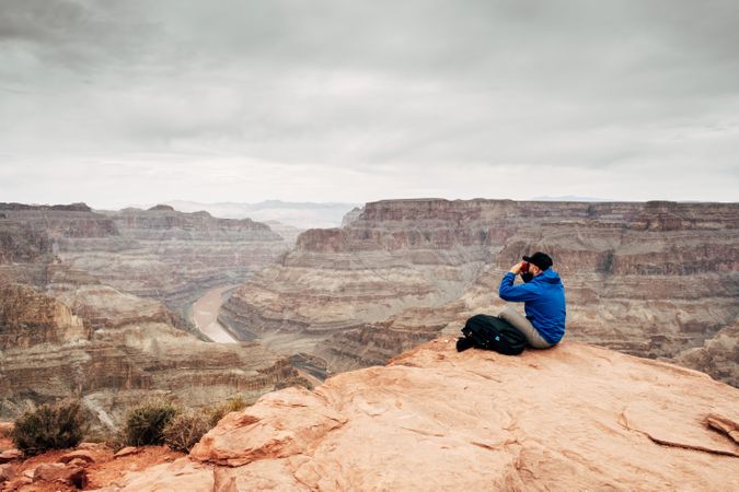 Male relaxing on cliff and admiring picturesque view