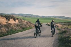 Men riding bicycles on road in desert hills