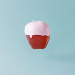 Red apple with pink syrup on pastel blue background