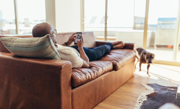 Man using mobile phone lying on a sofa