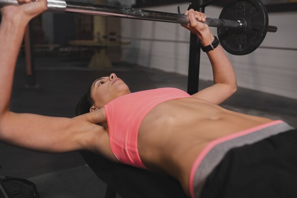 Athletic woman training with barbells in gym