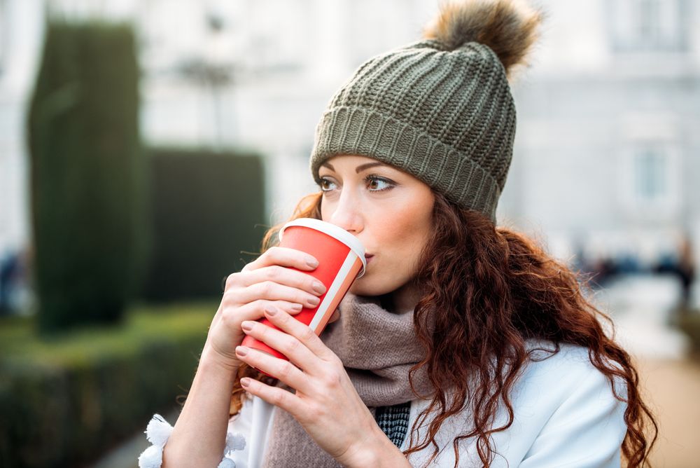 Beautiful woman drinking coffee in the streets of Madrid on winter