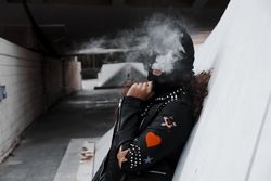 Woman in mask and jacket smoking on street