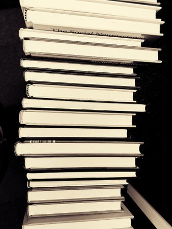 Stack of books in against dark background in grayscale