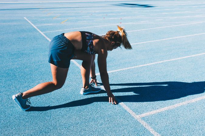 Young woman in starting position on a running track