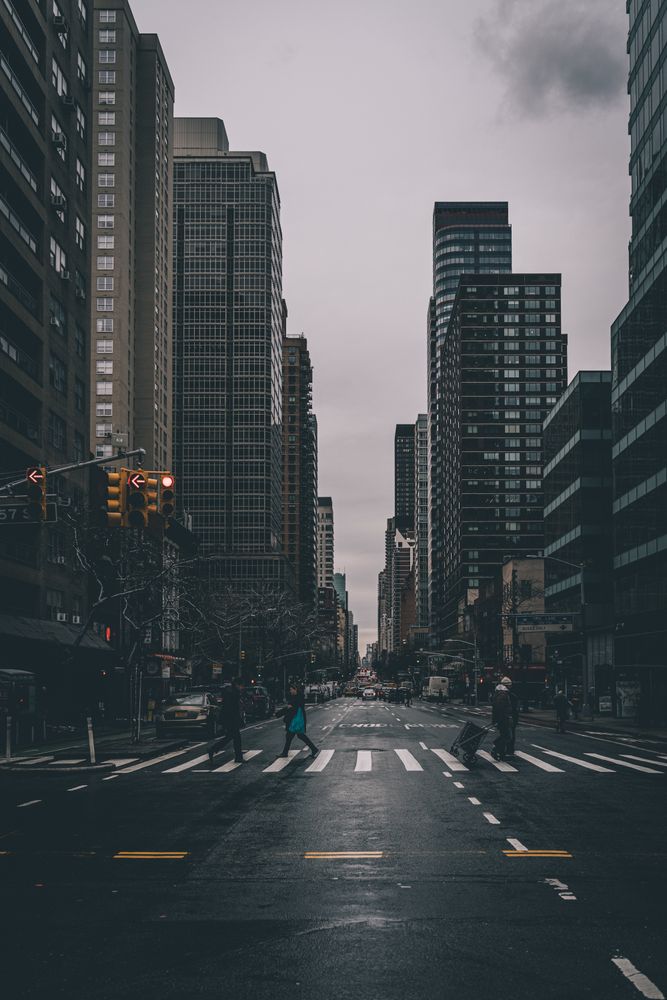 Cars on road between high rise buildings under dim sky