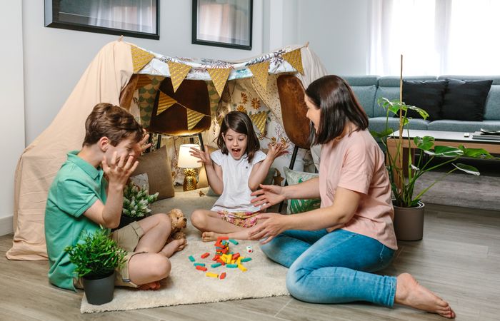 Happy family laughing and shouting together as a tower of wooden stacking piece game falls