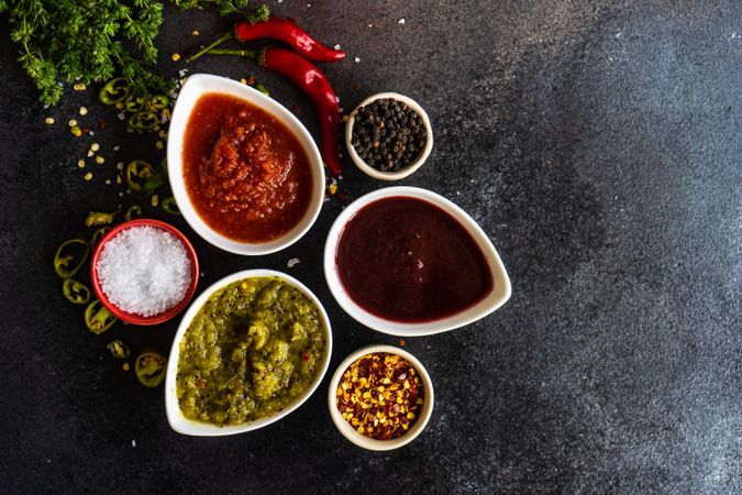 Top view of variety of traditional Georgian satsebeli sauces with kiwi, tomato and berried on stone background with copy space