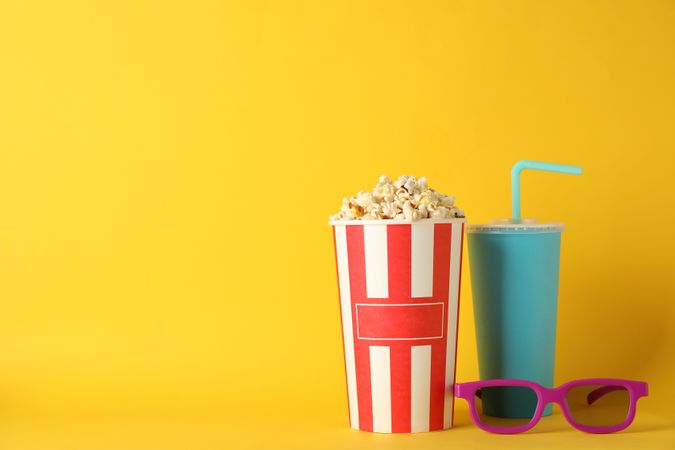 Bucket with popcorn, drink and 3d glasses on yellow background, space for text