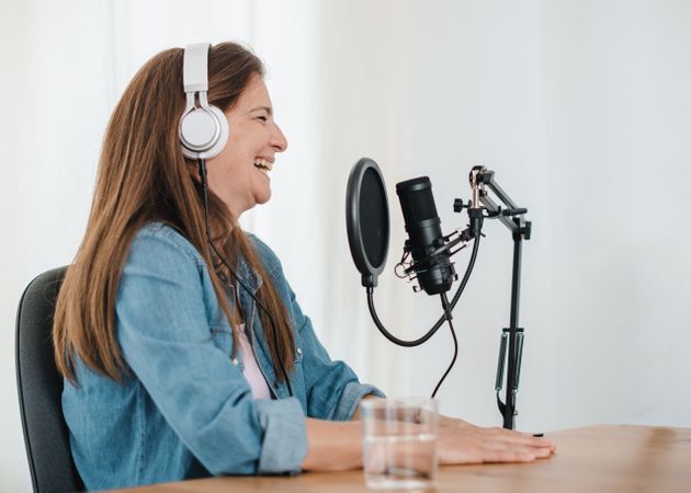 Cheerful woman in headphones recording podcast