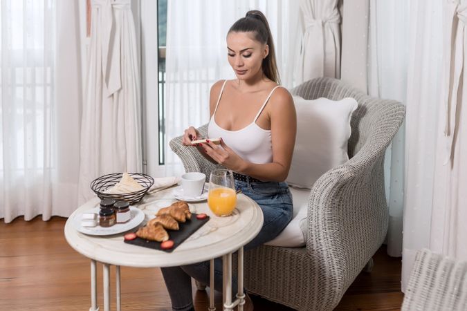 Woman spreading butter over bread for a breakfast in a hotel room