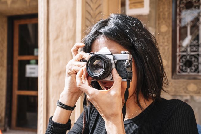 Female photographer taking picture with camera on street