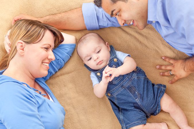 Young  Couple Laying With Their Infant On A Blanket