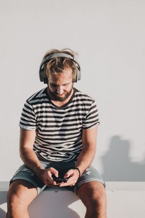 Young male sitting with smartphone and headphones