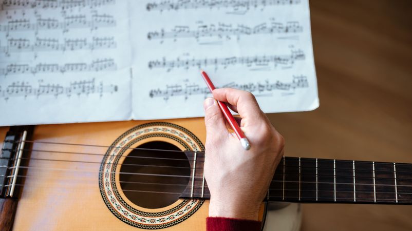 Man hands with sheet music playing guitar