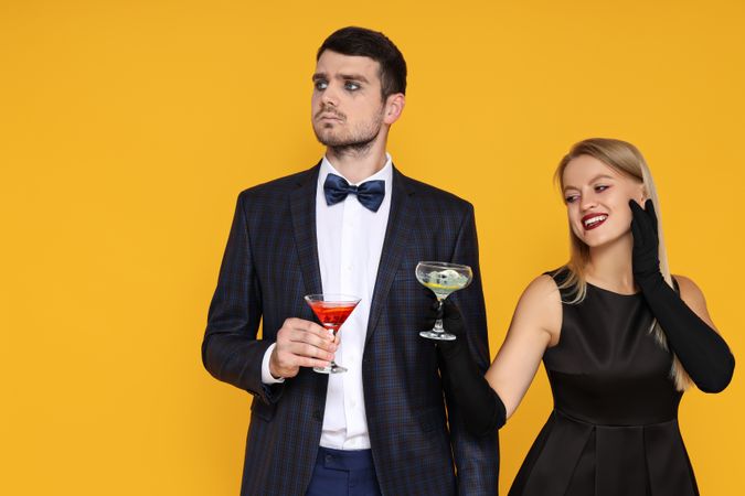 A woman and a man in Halloween costumes on a yellow background