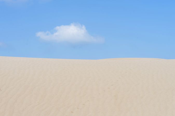 Lonely cloud over a dessert dune against blue sky