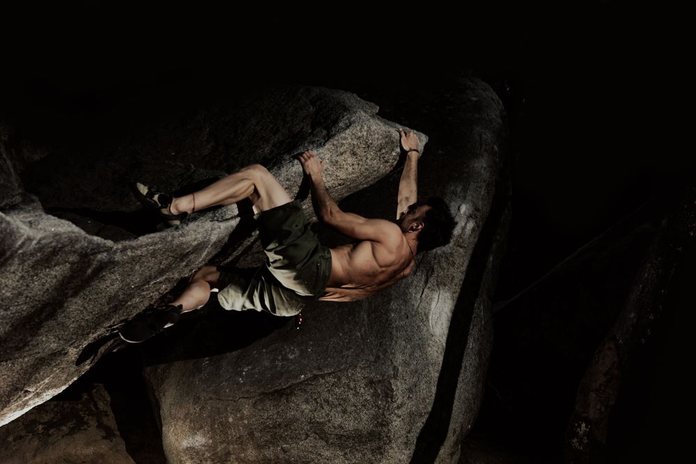 Man practicing rock climbing among large rocks in a forest