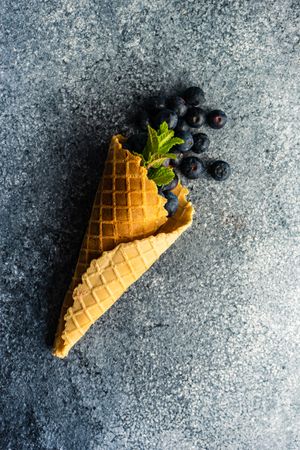 Waffle cone with fresh blueberries on grey counter