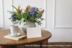 Blank card leaning on vase of flowers on table with cup of coffee 5kRVgW