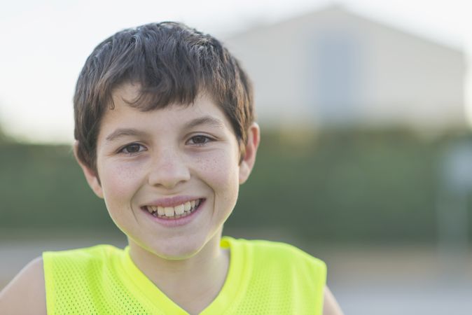 Portrait of a young teen wearing a yellow basketball sleeveless smiling