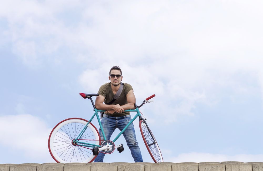 Male standing with bike on roof with beautiful blue sky and clouds
