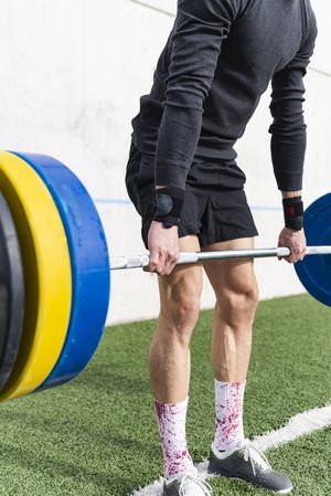 Man training with barbell on sports ground